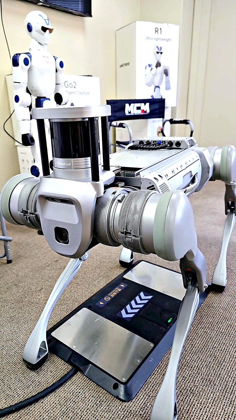Close-up of the Unitree B2 front cameras and RoboSense LiDAR standing over the charging station